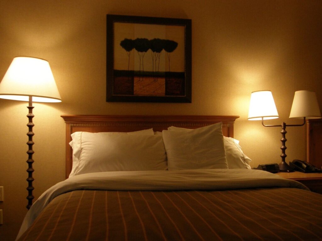 A bed room with a neatly made bed and two lamps