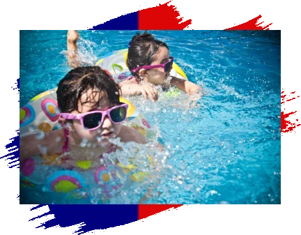 Two children swimming in a pool with goggles on.
